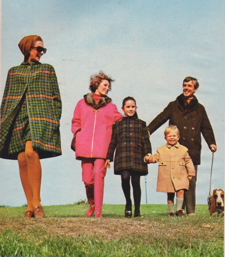 Photo of three adults, two children, and a basset hound taking a walk outdoors