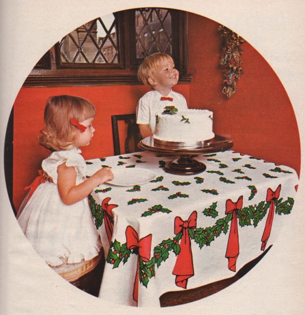 Photo of two children sitting at a table with a Christmas cake